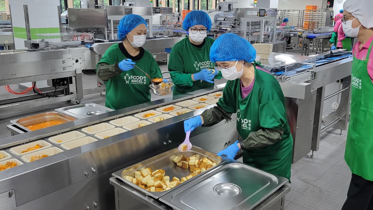 Volunteers preparing and portioning meals in a community kitchen, Julia M Cameron on Pexels.